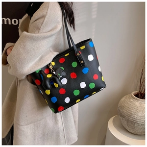 Détail d'un grand sac cabas noir à pois multicolores avec un petit pendentif de chien