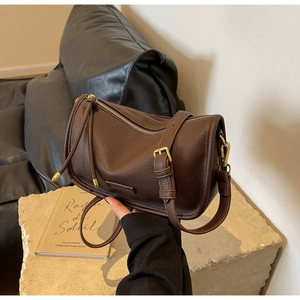 Detail of dark brown lychee leather texture and golden metal buckle on Boston bag