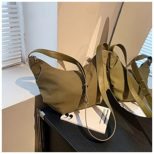 Close-up of olive green dumpling bag showing textured fabric and leather strap