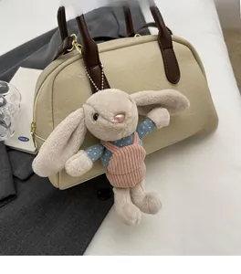 Cute bunny plush pendant with corduroy trousers hanging on a stylish leather bag
