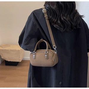 Brown matte leather tote with adjustable strap shown on model wearing black coat