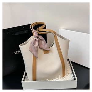 Detail of cream pebbled leather tote bag with brown straps and a floral silk scarf handle