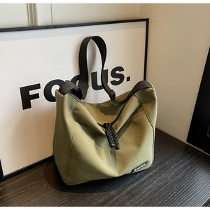 Detailed macro view of olive green nylon tote bag with black woven zipper and brand logo