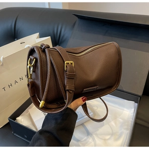 Close-up of dark brown litchi leather texture and gold hardware on Boston bag