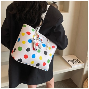 Détail d'un grand sac cabas avec des pois colorés et un porte-clés en forme de chien