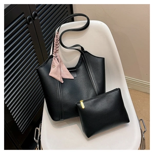 Detail of black pebbled leather tote bag set with floral silk scarf on a white chair