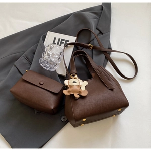 Detail of dark brown lychee leather bucket bag set with cute monkey charm accessory