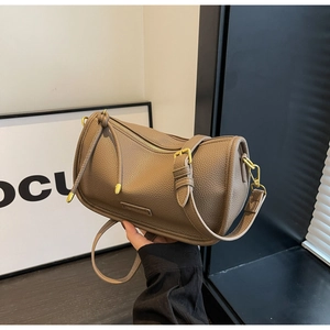 Close-up of brown litchi leather Boston bag with gold hardware and fine shoulder strap