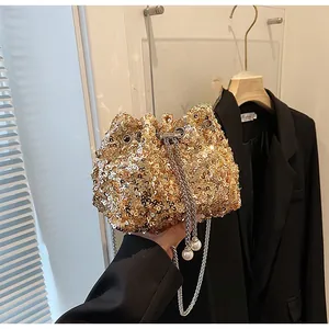 Détail d'un sac seau doré à paillettes avec chaîne et pendentifs en perles