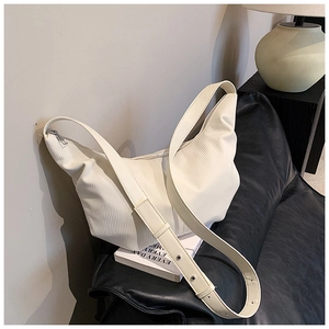 Close-up of beige pleated crescent bag with adjustable strap and silver zipper detail