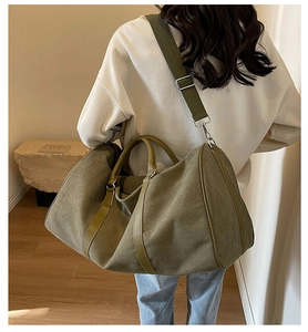 Detail of army green canvas travel bag featuring reinforced leather handles and wide strap