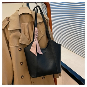 Detailed close-up of a black lychee texture tote bag with a pink silk scarf accent