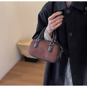 Detail of contrast-color suede handbag featuring brown textured panel and smooth leather