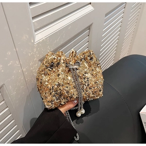 Détail du sac seau à paillettes dorées avec chaîne argentée et ornements en perles