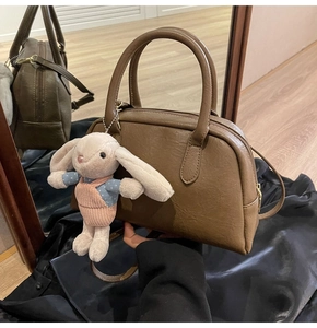 Detail of dark brown Boston bag with smooth faux leather texture and cute rabbit charm