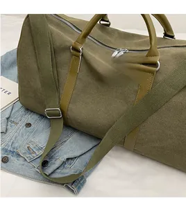 Detail of army green canvas duffel bag with leather handles and removable shoulder strap