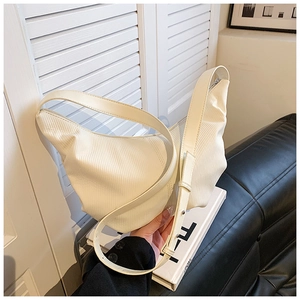 Detailed close-up of cream pleated crescent bag with adjustable strap and silver zipper