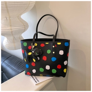Détail du sac cabas noir à pois colorés avec charm chien posé sur un canapé