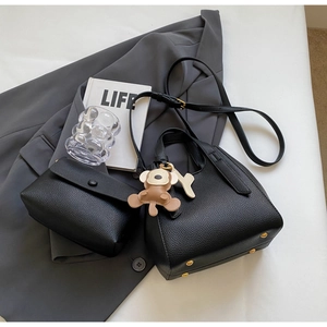 Close-up of black lychee texture bucket bag set with protective gold metal feet and monkey charm