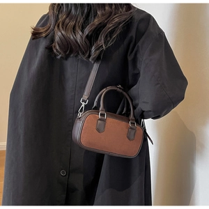 Detail view of brown matte leather shoulder bag with adjustable strap on a model