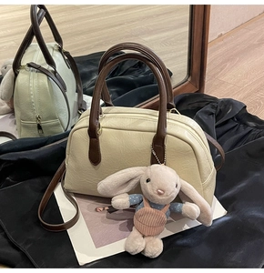 Detail of cream Boston bag with dark brown handles and cute plush bunny charm
