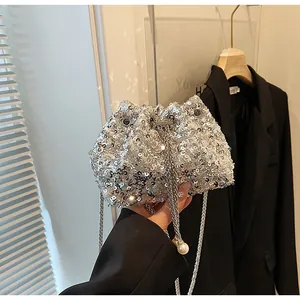 Gros plan sur un sac seau à paillettes argentées avec cordon et détails de perles blanches