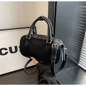 Detail of a black mini Boston bag featuring circular handles and silver metal hardware