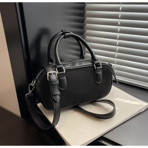 Detail shot of black matte suede handbag with silver metal buckles and double zipper design