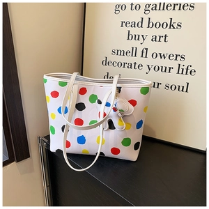 Détail d'un sac cabas blanc à pois colorés avec un charmant pendentif chien