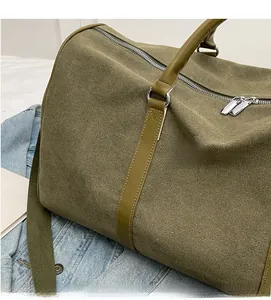 Detail of olive green canvas travel bag showing leather handles and metal dual zippers