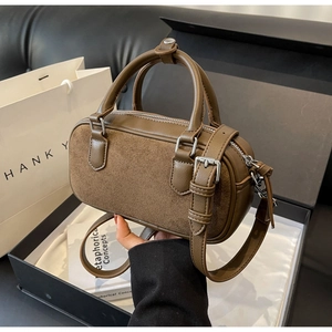Detail of brown suede Boston bag with leather handles and silver metal hardware