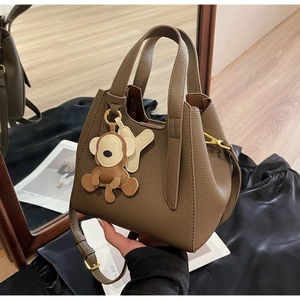 Detailed view of dark brown pebbled leather bucket bag with cute monkey charm