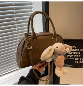 Detail of dark brown Boston bag with smooth leather texture and plush rabbit charm