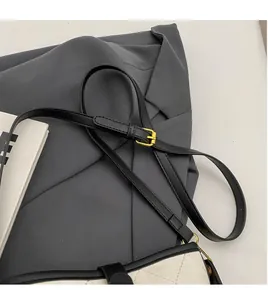 Detail of adjustable black leather strap with gold buckle on white quilted bucket bag