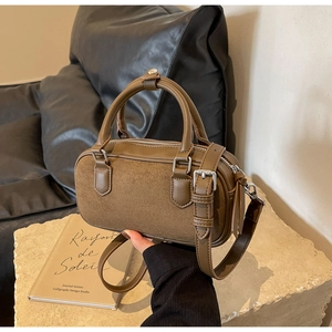 Close-up of olive brown Boston bag with suede stitching and silver metal details