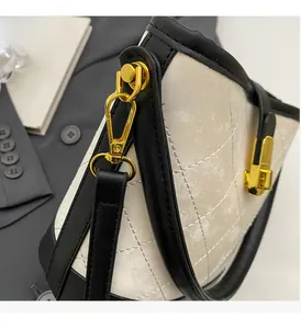 Detail of polished gold hardware and quilted texture on a cream bucket bag