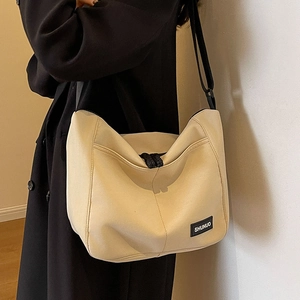 Cream nylon tote bag with black adjustable strap and brand logo for daily commute