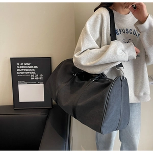 Close-up of a large black canvas travel bag worn on one shoulder showing texture