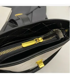 Macro detail of the smooth golden zipper and quilted texture on the contrast bucket bag