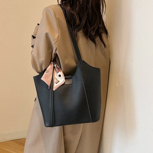 Black leather tote bag with pink floral scarf shown on a model in a beige trench coat