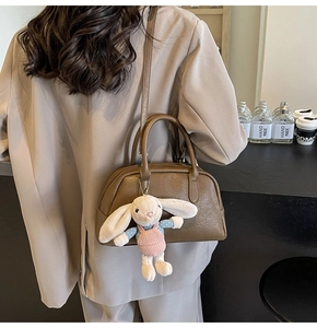 Close-up of retro brown Boston bag with a cute plush rabbit pendant and fine leather texture