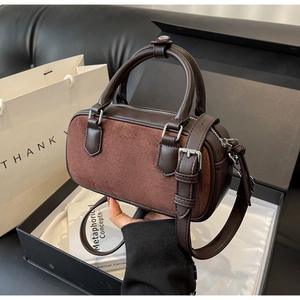 Detail of dark brown Boston bag featuring matte suede textures and silver hardware