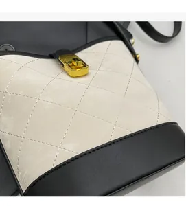 Detail of quilted beige leather contrast with black base and gold lock on the bucket bag
