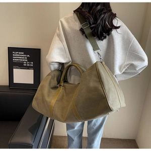 Detail of army green canvas travel bag with leather accents and adjustable shoulder strap