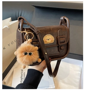 Détail du sac bandoulière vintage en cuir PU marron avec broderie cartoon et pompon doux