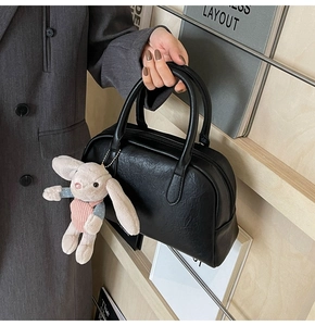 Detail of black Boston bag with pebbled leather texture and cute plush rabbit charm