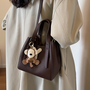 Deep brown lychee leather bucket bag with a cute monkey charm for women