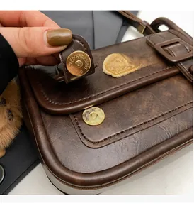 Détail d'un sac en cuir marron foncé montrant le fermoir magnétique doré circulaire