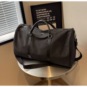 Close-up of large black canvas travel bag with leather handles on a metal stand