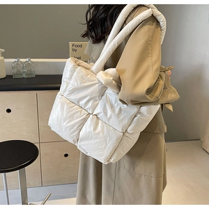 Detail view of a quilted puffer tote bag with wide soft straps in cream white finish